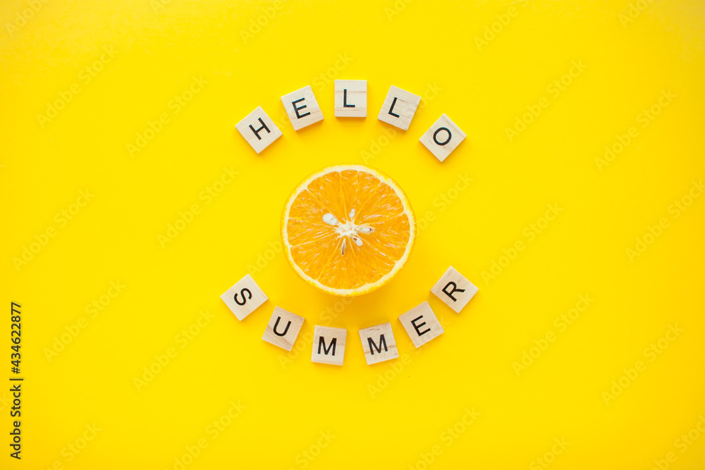 The inscription from wooden cubes hello summer and oranges on a bright yellow background. High quality photo