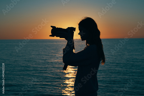 woman resting on the sea with a camera and sunset in the background