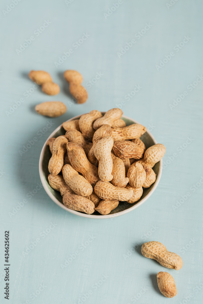 Pile of Peanuts in a bowl on a light blue background Pile of Peanuts in a bowl on a light blue background