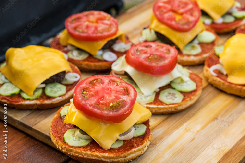Hamburger holiday menu. Burgers are prepared in outdoors from buns, fried cutlets, vegetables, slice of cheese, tomato, ketchup, sauce