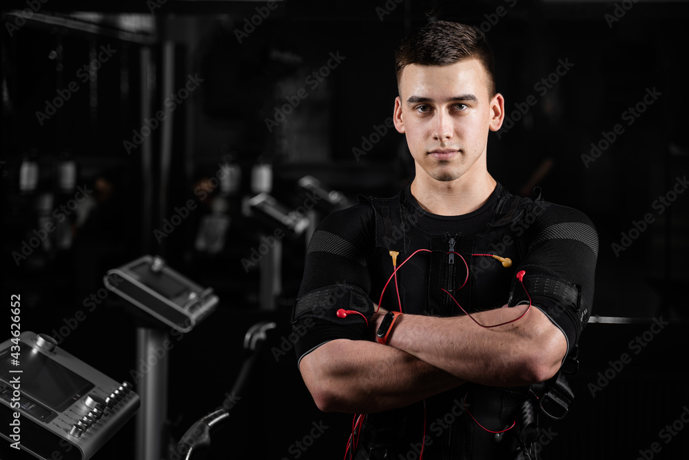 Muscular man trainer weared ems electrical body suit in gym. electro impulse stimulation with contactors on suit. - obrazy, fototapety, plakaty 