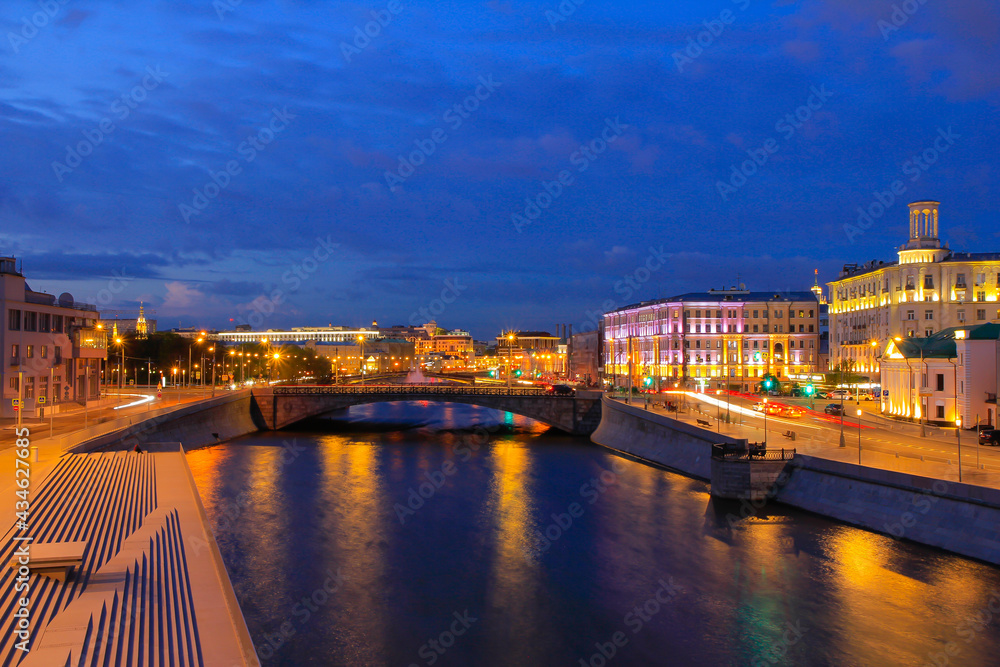 A bright blue hour in Moscow - with a view of the river, bridge, embankments and old houses - in the light of evening lamps.