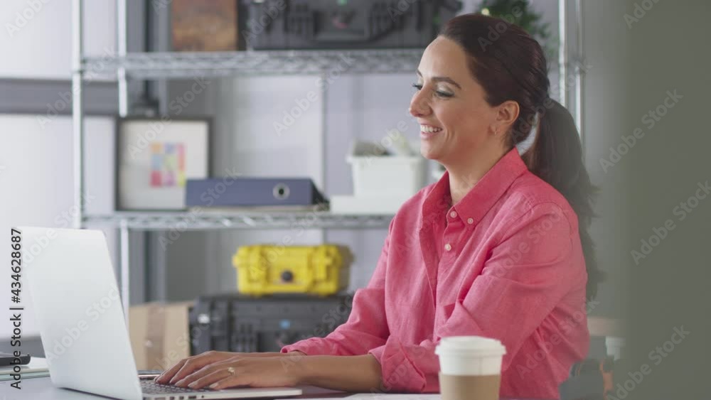 Businesswoman In Office Making Video Call At Desk On Laptop Businesswoman In Office Making Video Call At Desk On Laptop