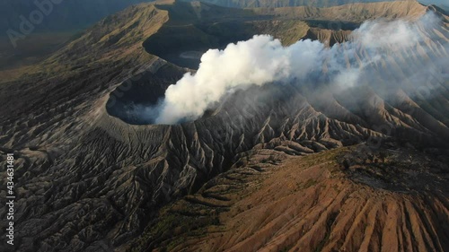 Clouds of smoke on volcano, Mount Bromo, Indonesia. Aerial view of mount as active volcano with crater in depth. Brown dirt around.
