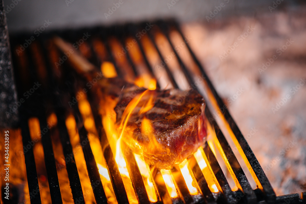 Juicy steak is grilled in a restaurant. Roasting meat in the fire on the grill. Juicy steak is grilled in a restaurant. Roasting meat in the fire on the grill.
