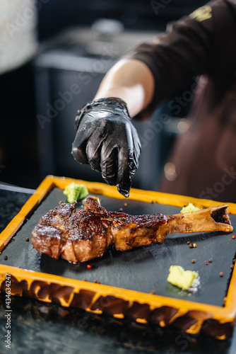 Canvas Print A professional chef beautifully serves a juicy grilled steak with butter and seasonings