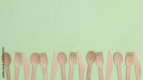 Eco friendly zero waste kitchen utensils cutlery move left right on bottom of light green background. Stop motion