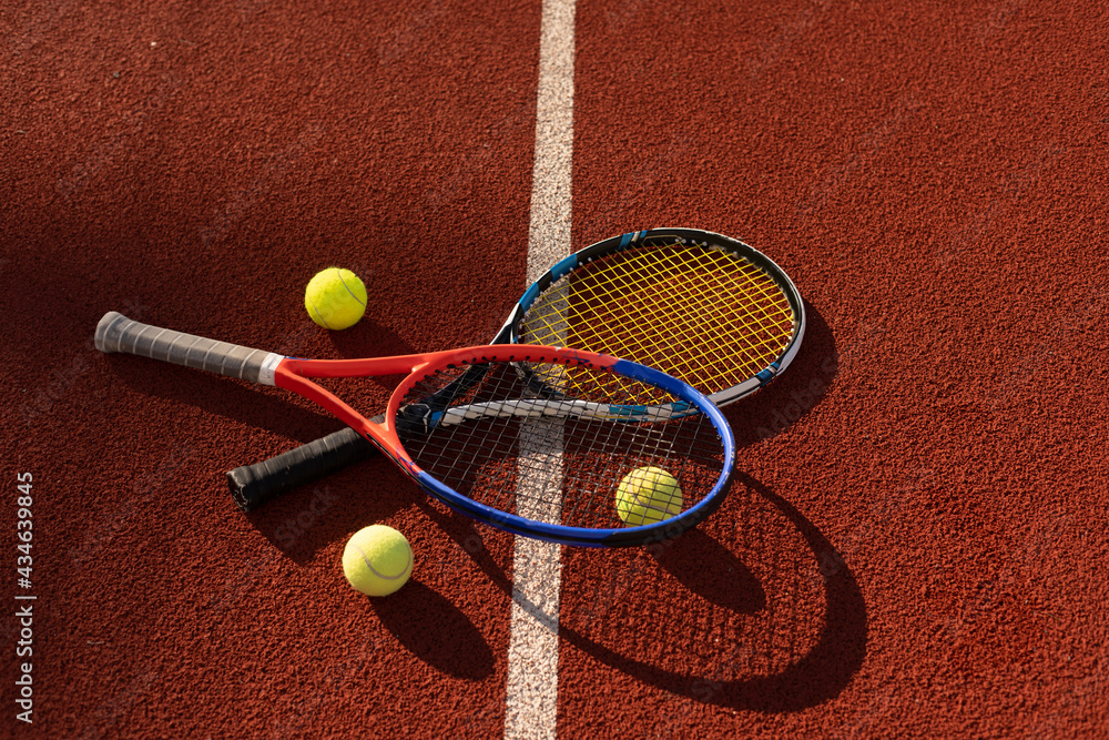 Close up view of two tennis rackets and balls on the tennis court.