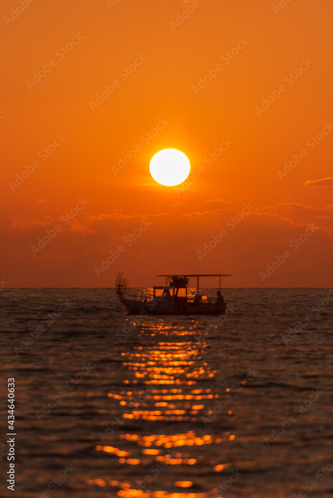 Fishing boat at sunset. Evening Mediterranean sea and fishing boat on the horizon. Focus photos on the sun.