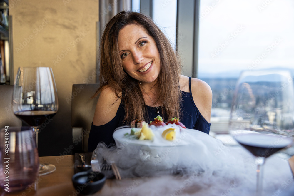 Pretty woman smiles at restaurant as dry ice smoke rolls over Fresh Bluefin Tuna Sushi Nigiri
