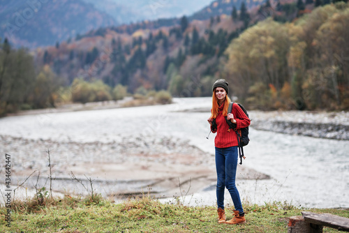 traveler with backpack on nature in autumn forest and transparent river mountains landscape