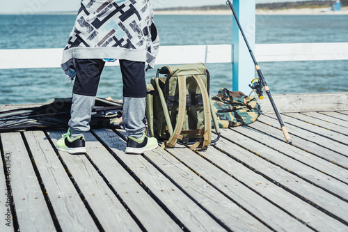 Fototapeta Naklejka Na Ścianę i Meble -  Young man with fishing rod on the Baltic sea pier. People leisure hobby concept.
