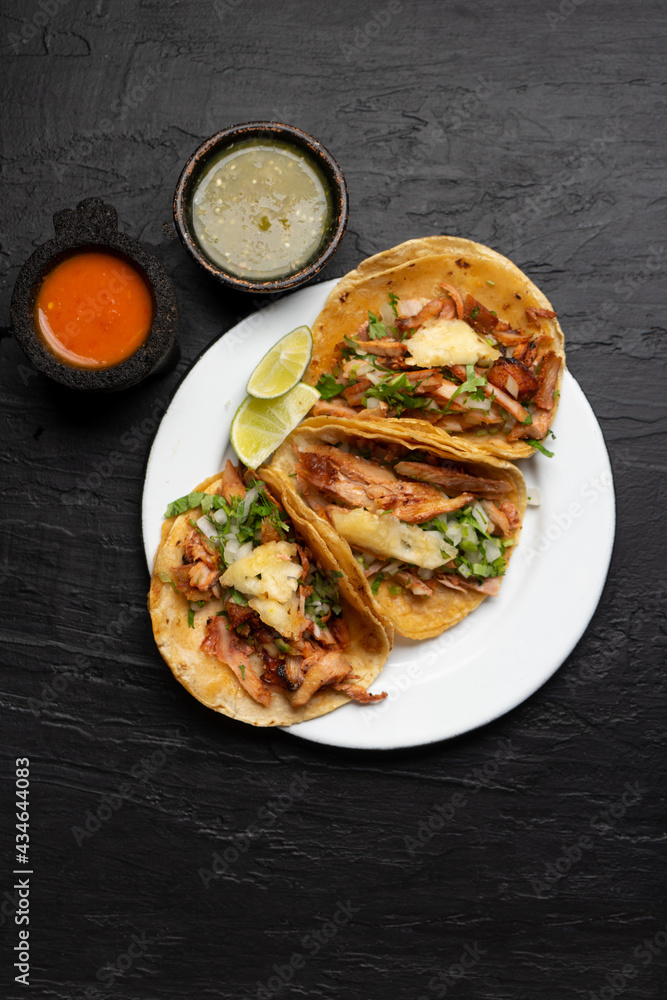 Pork tacos called al pastor with pineapple on dark background. Mexican tacos