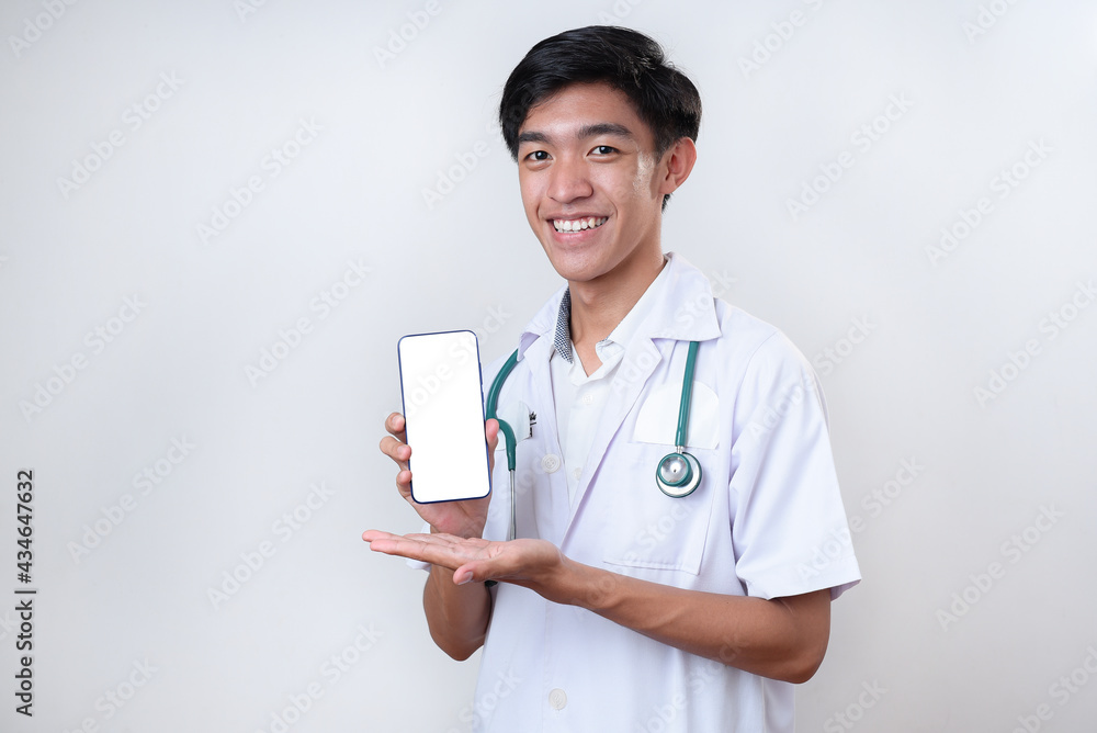 Portrait of young handsome Asian doctor showing phone with blank screen and copy space for medical app ads Portrait of young handsome Asian doctor showing phone with blank screen and copy space for medical app ads