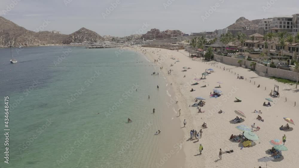 People enjoying Medano Beach shoreline, Cabo San Lucas, Los Cabos, México. Aerial establisher People enjoying Medano Beach shoreline, Cabo San Lucas, Los Cabos, México. Aerial establisher
