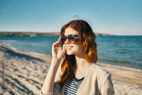 happy woman on the beach near the sea in the mountains glasses on the face red hair model landscape