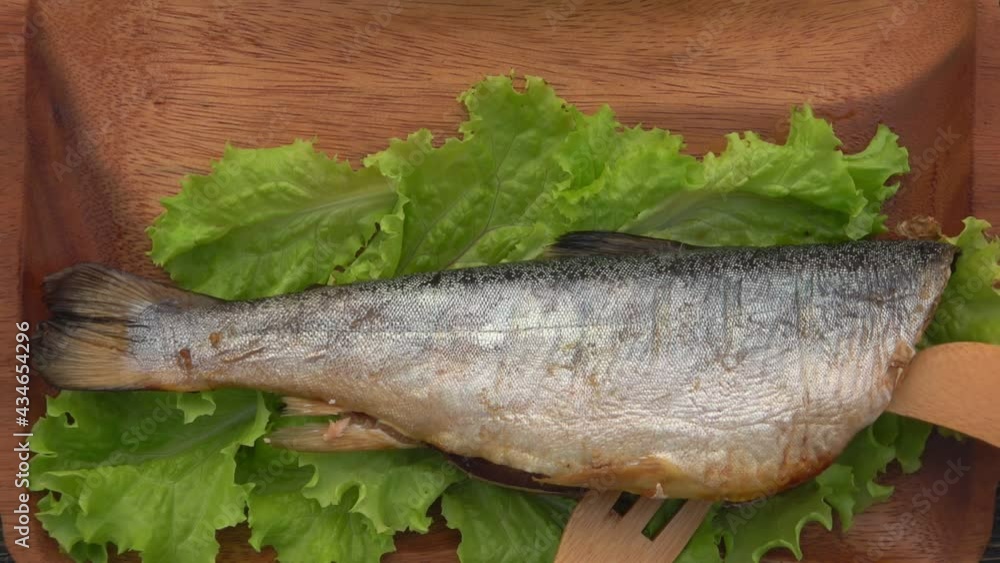 Top view of the delicious juicy grilled red char fish opened with a wooden fork