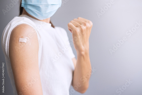Happy Woman showing her arm with bandage after receiving vaccine. Vaccination, immunization, inoculation and Coronavirus ( Covid-19 ) pandemic