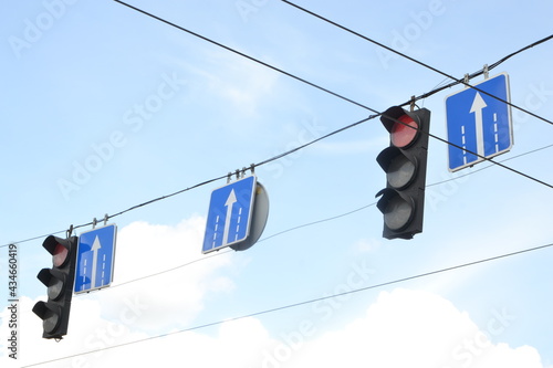 Two traffic lights at intersection on street against blue sky on street, turned on red light means stop for driverless vehicle. Traffic signals concept photo