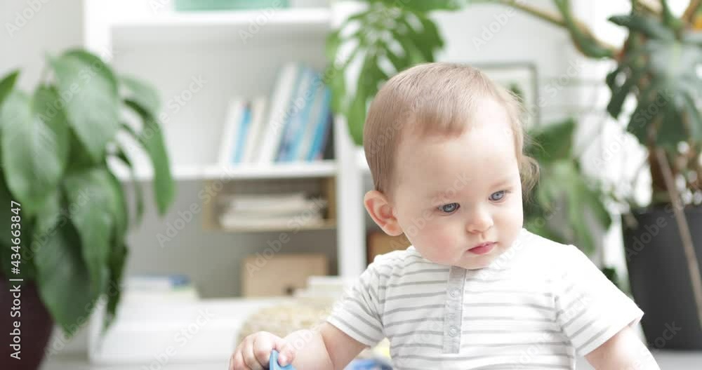 Cute baby boy close up playing with colourful wooden blocks, contemporary, home interior 50fps