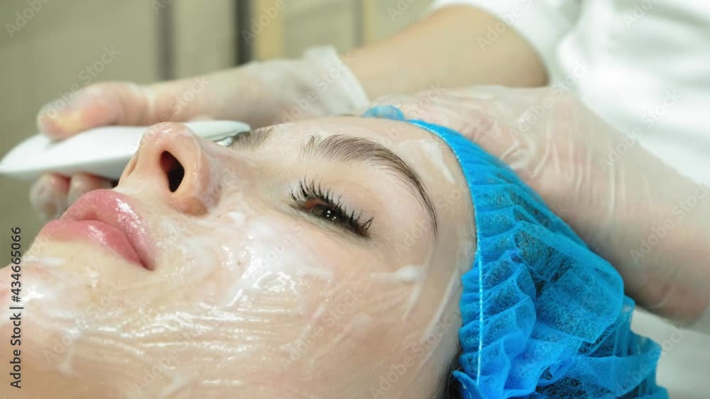 A female cosmetologist gives a young girl a facial massage A female cosmetologist gives a young girl a facial massage