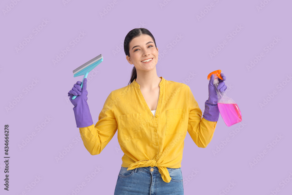 Young woman with detergent and squeegee on color background Young woman with detergent and squeegee on color background