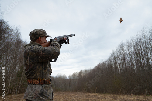 Canvas Print a hunter shoots a flying woodcock in the evening twilight