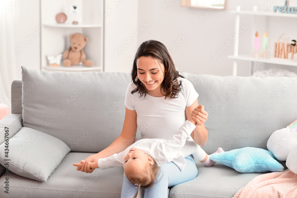 Happy woman and her little daughter playing on sofa at home Happy woman and her little daughter playing on sofa at home