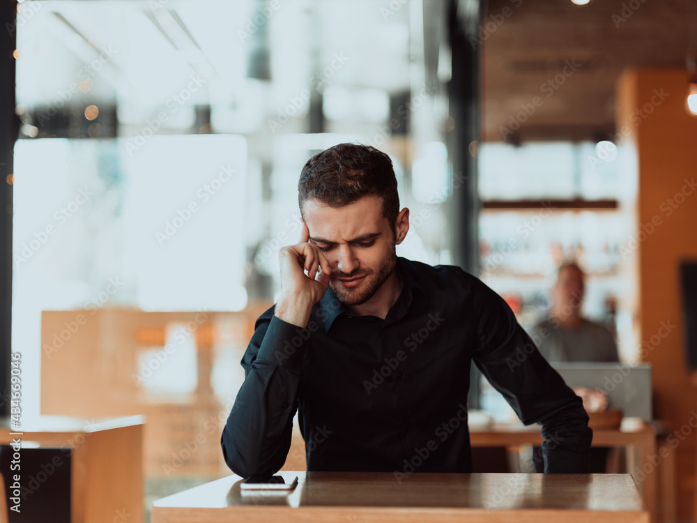 a tired businessman sitting in a cafeteria on a break from work. a tired businessman sitting in a cafeteria on a break from work.