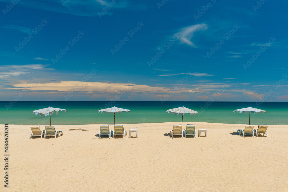 Beach chairs with an umbrella and a beautiful beach on a sunny day. Summer vacation and nature travel adventure concept.