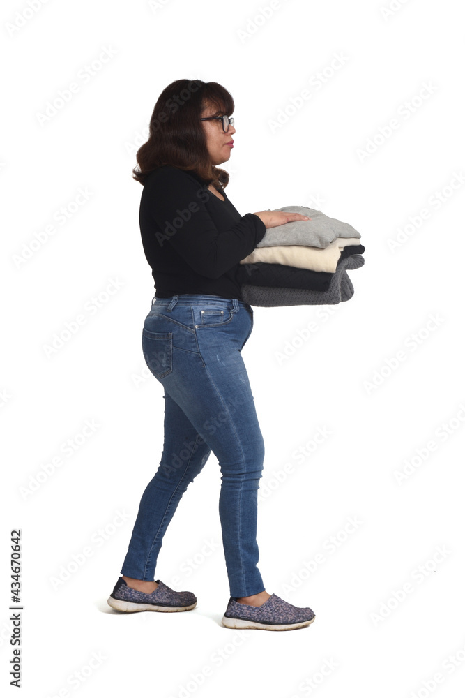 side view of a latin woman walking and holding a pile of clean clothes on white background side view of a latin woman walking and holding a pile of clean clothes on white background