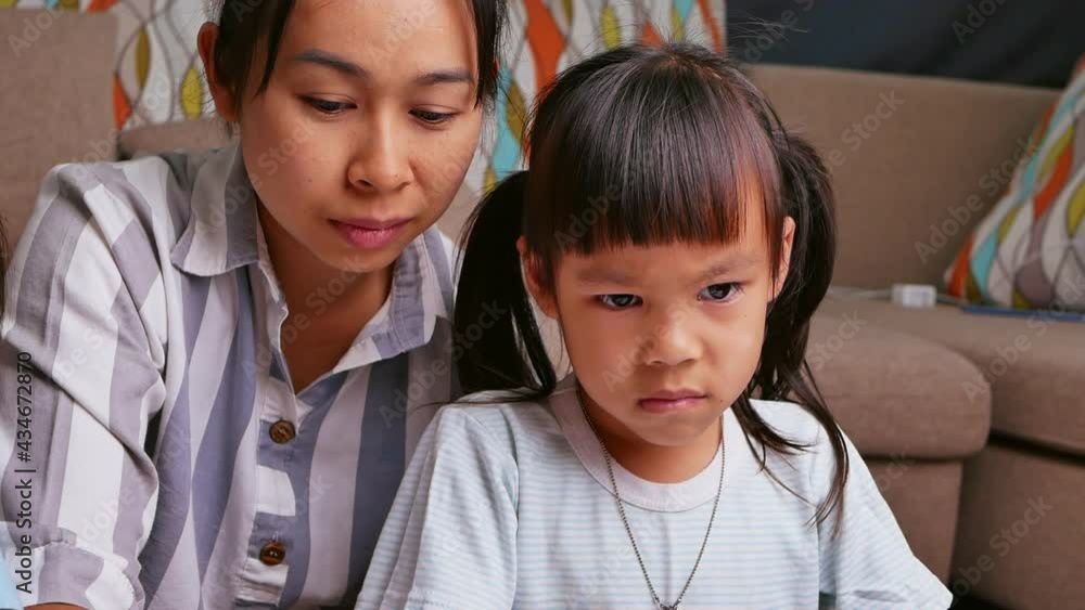 Sad schoolgirl studying homework math during her online lesson at home with mother. Home school concept. Kindergarten online education. Sad schoolgirl studying homework math during her online lesson at home with mother. Home school concept. Kindergarten online education.