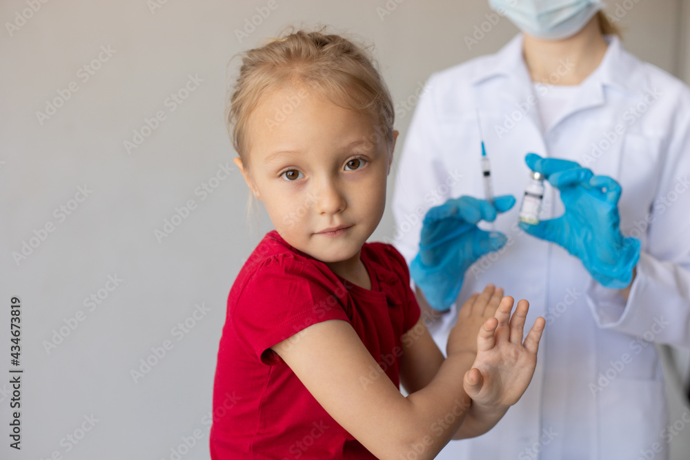 Child covers himself with crossed arms from the doctor with a syringe. Child covers himself with crossed arms from the doctor with a syringe.