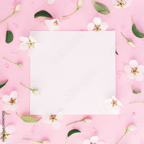 White flowers pattern around white papers with pink paper clip on pink background, copy space in centre, vertical photo, spring time © Anastassiya 