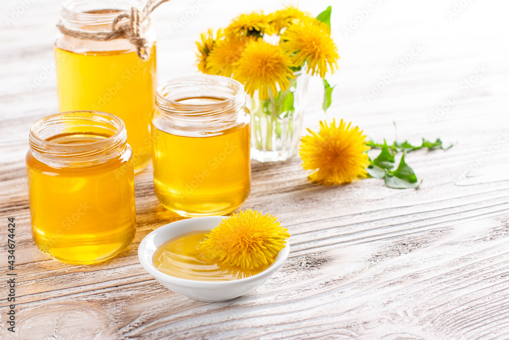 Dandelion honey in a jar and fresh flowers on white table. Copy space Dandelion honey in a jar and fresh flowers on white table. Copy space