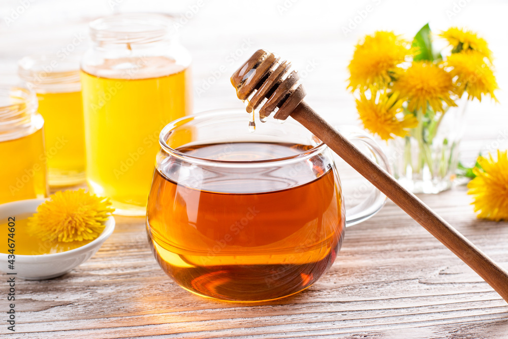 Herbal tea infusion of fresh dandelion leaf, with yellow blossoms and honey on wooden table. Herbal tea infusion of fresh dandelion leaf, with yellow blossoms and honey on wooden table.