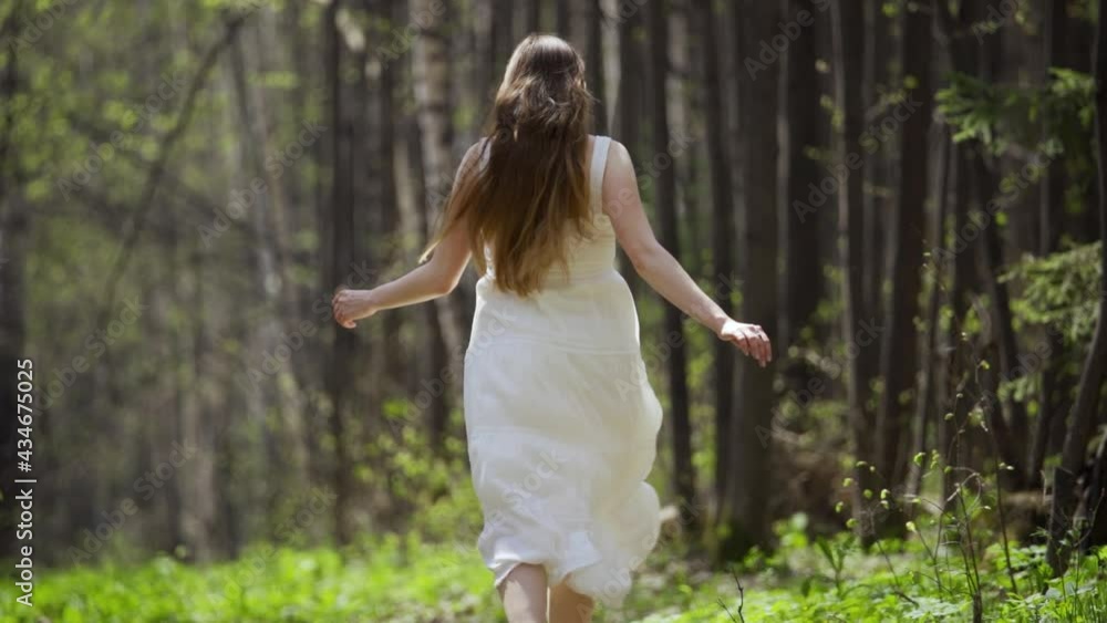 Beauty romantic young woman in long chiffon dress with gown running in the forest on sunset. Beautiful happy bride model girl enjoying nature outdoors. Slow motion Beauty romantic young woman in long chiffon dress with gown running in the forest on sunset. Beautiful happy bride model girl enjoying nature outdoors. Slow motion
