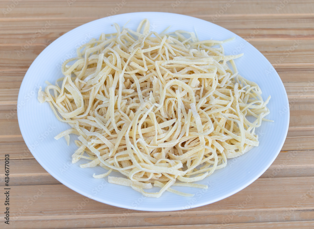 Fresh homemade pasta in a plate - wooden background. Recipe concept Fresh homemade pasta in a plate - wooden background. Recipe concept