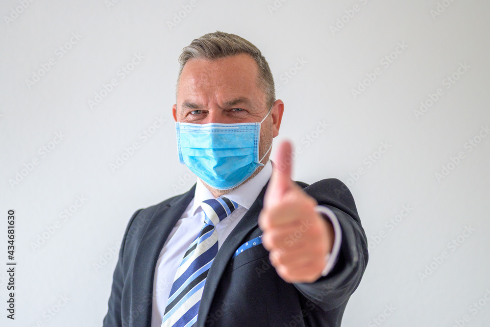 Smiling businessman wearing a face mask giving a thumbs up Smiling businessman wearing a face mask giving a thumbs up