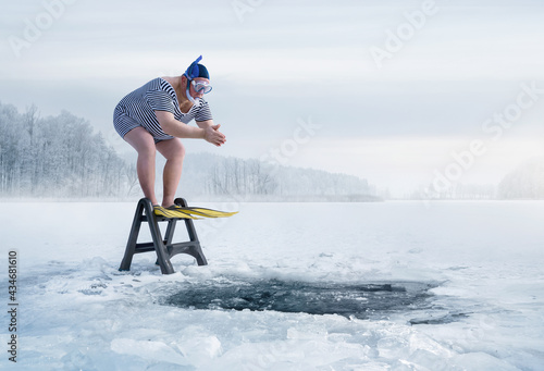 Fototapeta Fuunny overweight, retro swimmer about to jump into ice hole in the lake, with c