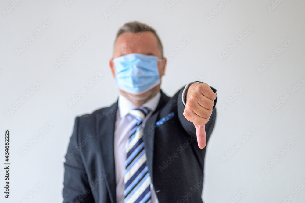 Businessman in face mask giving a thumbs down gesture Businessman in face mask giving a thumbs down gesture