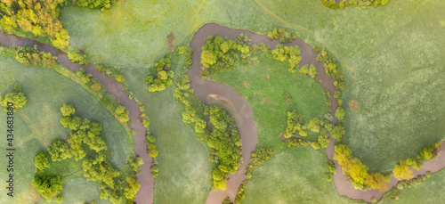 Принти на полотні Aerial view of river meander in the lush green vegetation of the delta
Top view of the valley of a meandering river among green fields and forests