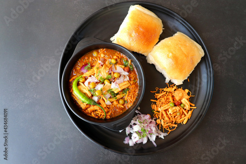 Spicy Misal Pav or usal Pav is a traditional snack or Chaat food from Maharashtra, India. Served with chopped onion, lemon wedges and farsan. Selective focus with copy space