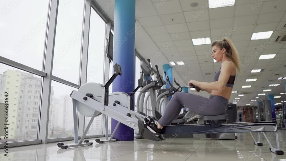 Young woman working out on row machine at gym exercising Young woman working out on row machine at gym exercising