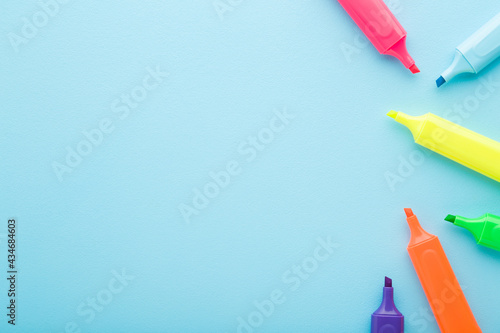 New colorful bright highlighters on light blue table background. Pastel color. Closeup. Empty place for text. Top down view.