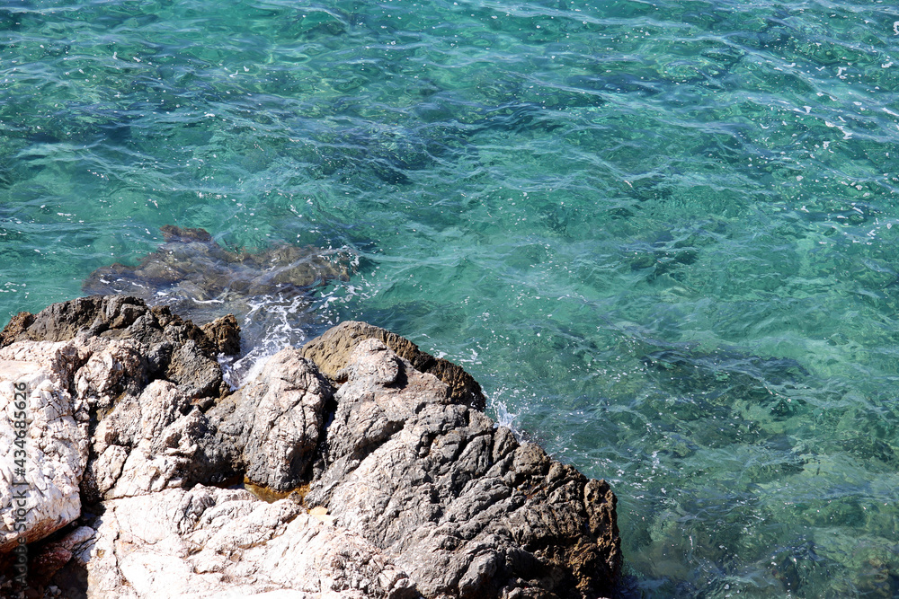 Rock and clean azure water on a beach. Coast of Mediterranean sea