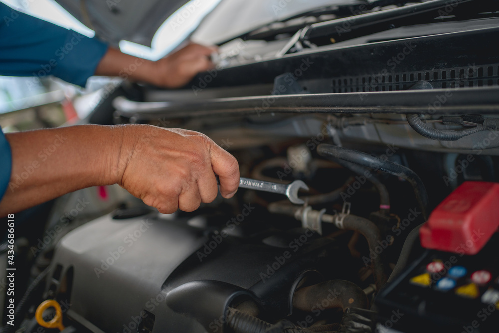 Hand of an auto mechanic is repairing the problematic car. Car service and maintenance concept. Hand of an auto mechanic is repairing the problematic car. Car service and maintenance concept.