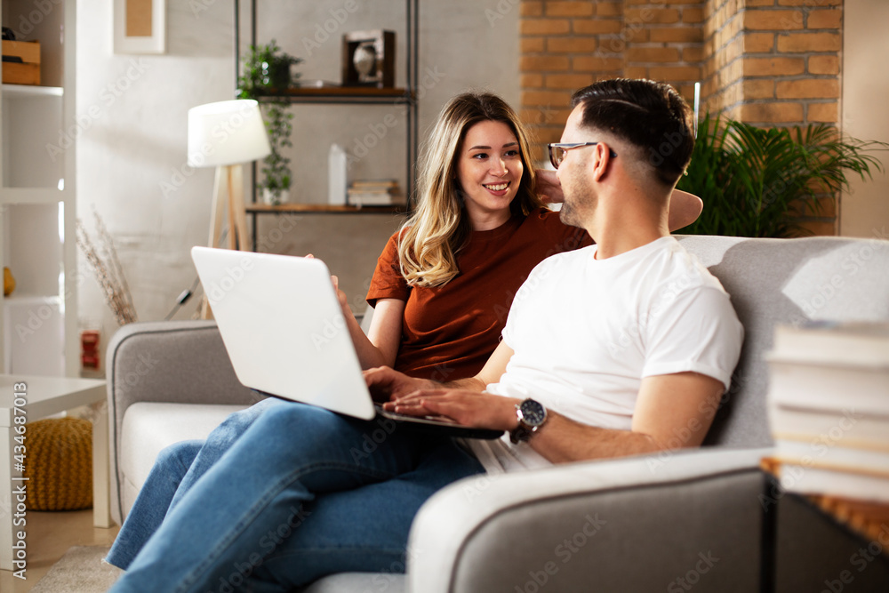  Happy young couple with laptop at home. Boyfriend and girlfriend watching movie on laptop.