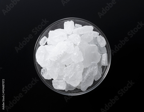 фотографія rock candy in a glass bowl set against a black background.