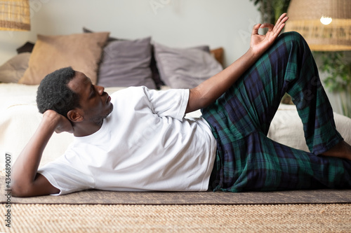 African yoga man doing anantasana pose working out at home photo